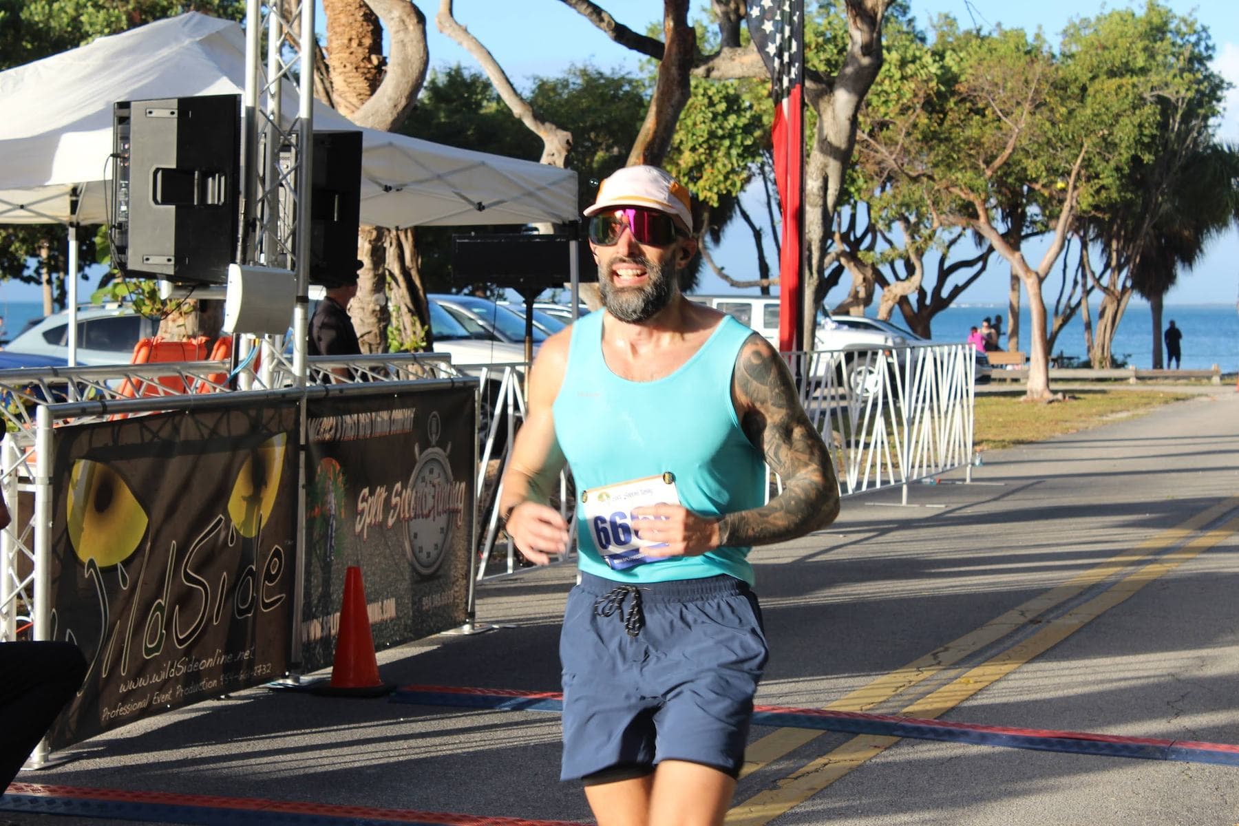 A runner in a teal tank finishing strong