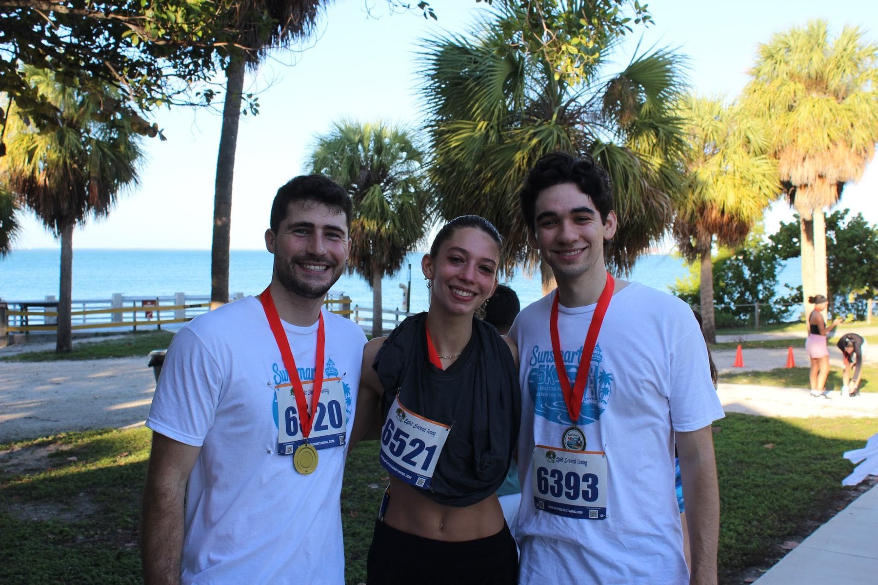 Three finishers with their medals by the water